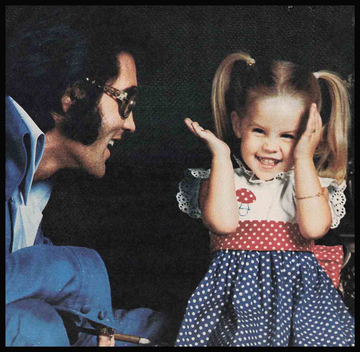 Elvis Presley playing peekaboo with young Lisa Marie